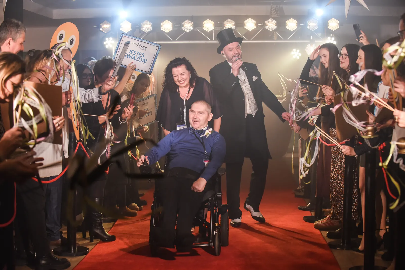 A guest arrives on the red carpet, welcomed by volunteers